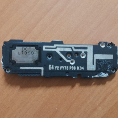 Peça eletrónica retangular preta com inscrições em branco sobre mesa de madeira clara