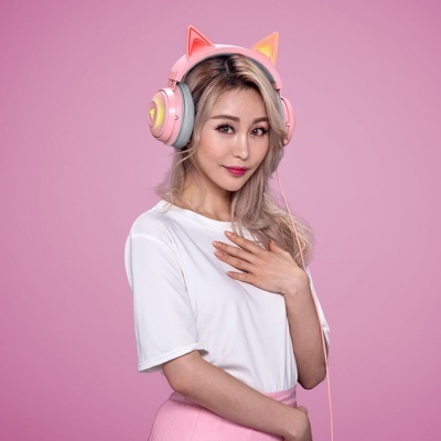 Mulher com auscultadores rosas com orelhas de gato iluminadas em fundo rosa