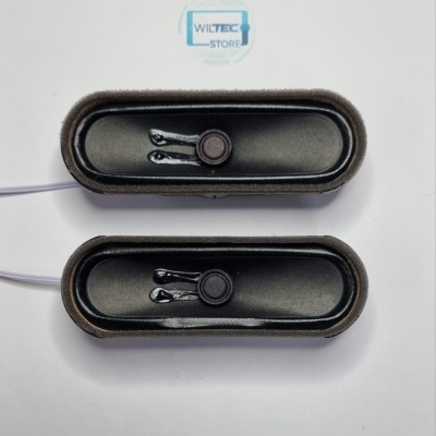 Dois altifalantes retangulares pretos com bordas de espuma cinzenta e fios brancos sobre superfície branca com logótipo WILTEC STORE.