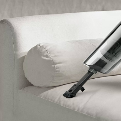 aspirador portátil a limpar sofá cinzento claro