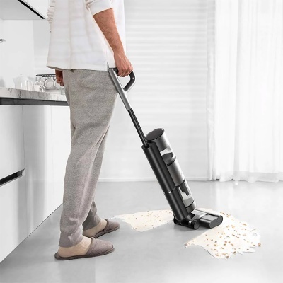 Aspirador vertical preto a aspirar líquido no chão branco