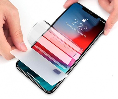 Smartphone preto com película protetora transparente a ser aplicada no ecrã