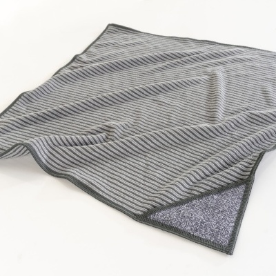 Manta cinzenta às riscas com bordas pretas sobre superfície branca