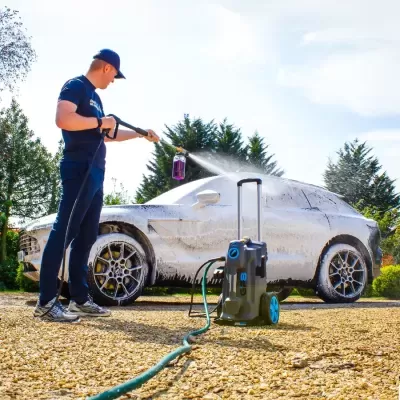 Homem a lavar carro com máquina de alta pressão ao ar livre