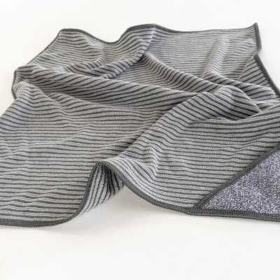 Toalha ou manta cinzenta com riscas finas pretas sobre fundo branco