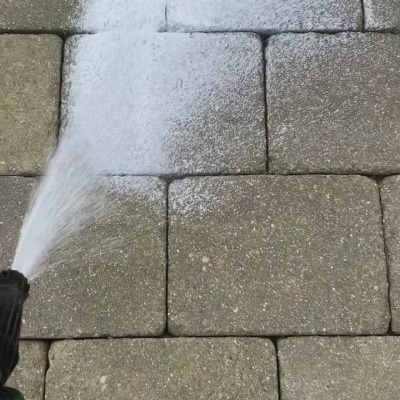 Borrifador a pulverizar água em pavimento de pedras cinzentas