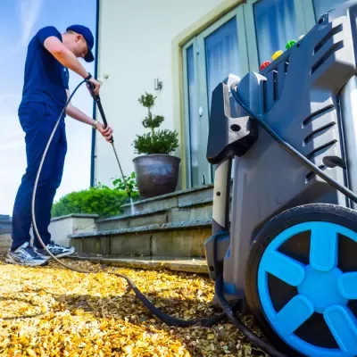Homem usando máquina de limpeza de alta pressão com rodas azuis ao ar livre