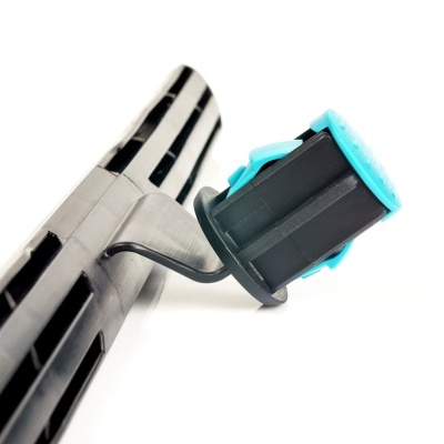 Espátula preta com ranhuras segurada por mão com luva preta e detalhes azuis