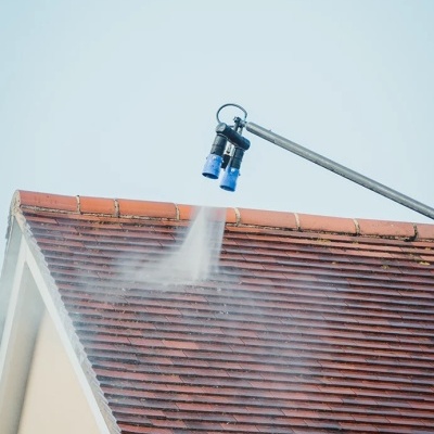 Esguicho de lavagem a alta pressão a limpar telhado de telhas vermelhas