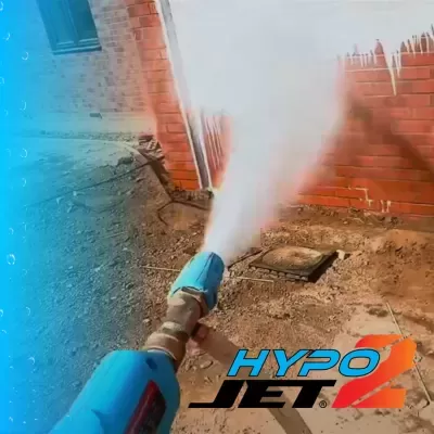 Lança de alta pressão a jorrar água junto a parede de tijolos