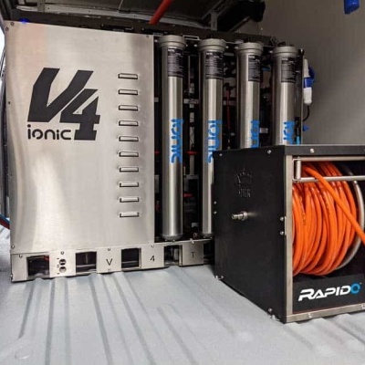 Sistema de purificação de água V4 Ionic com cartuchos e caixa preta com mangueira laranja.