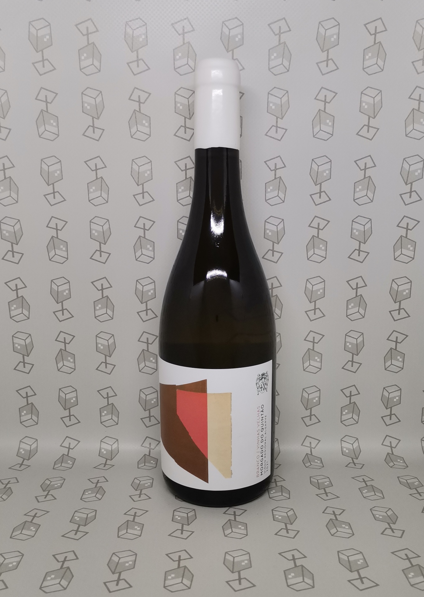 Garrafa escura com rótulo geométrico e tampa branca, fundo com padrão de cubos cinza
