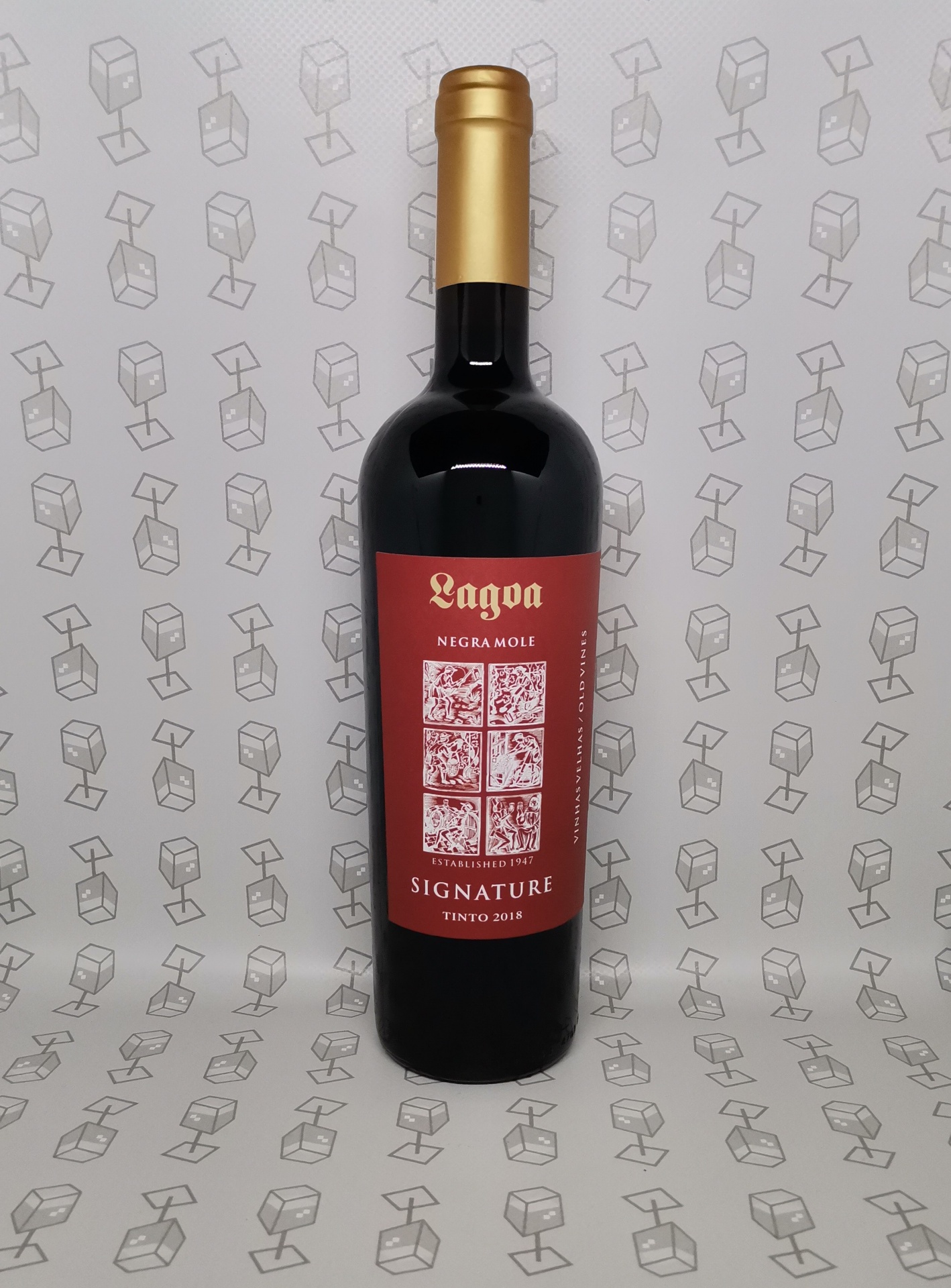 Garrafa de vinho tinto com rótulo vermelho e tampa dourada em superfície com padrão geométrico