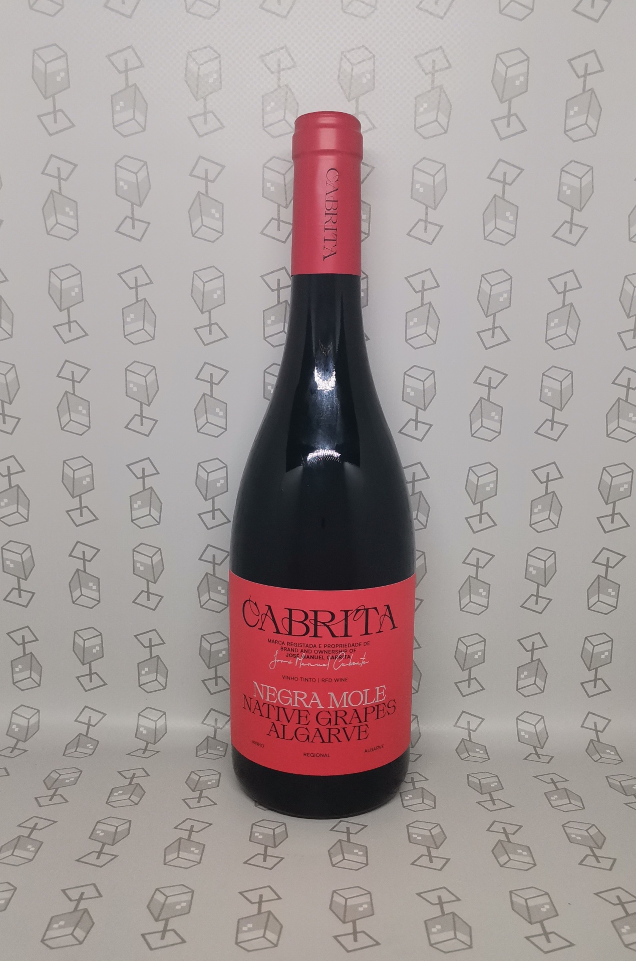 Garrafa de vinho tinto com rótulo vermelho e texto em preto