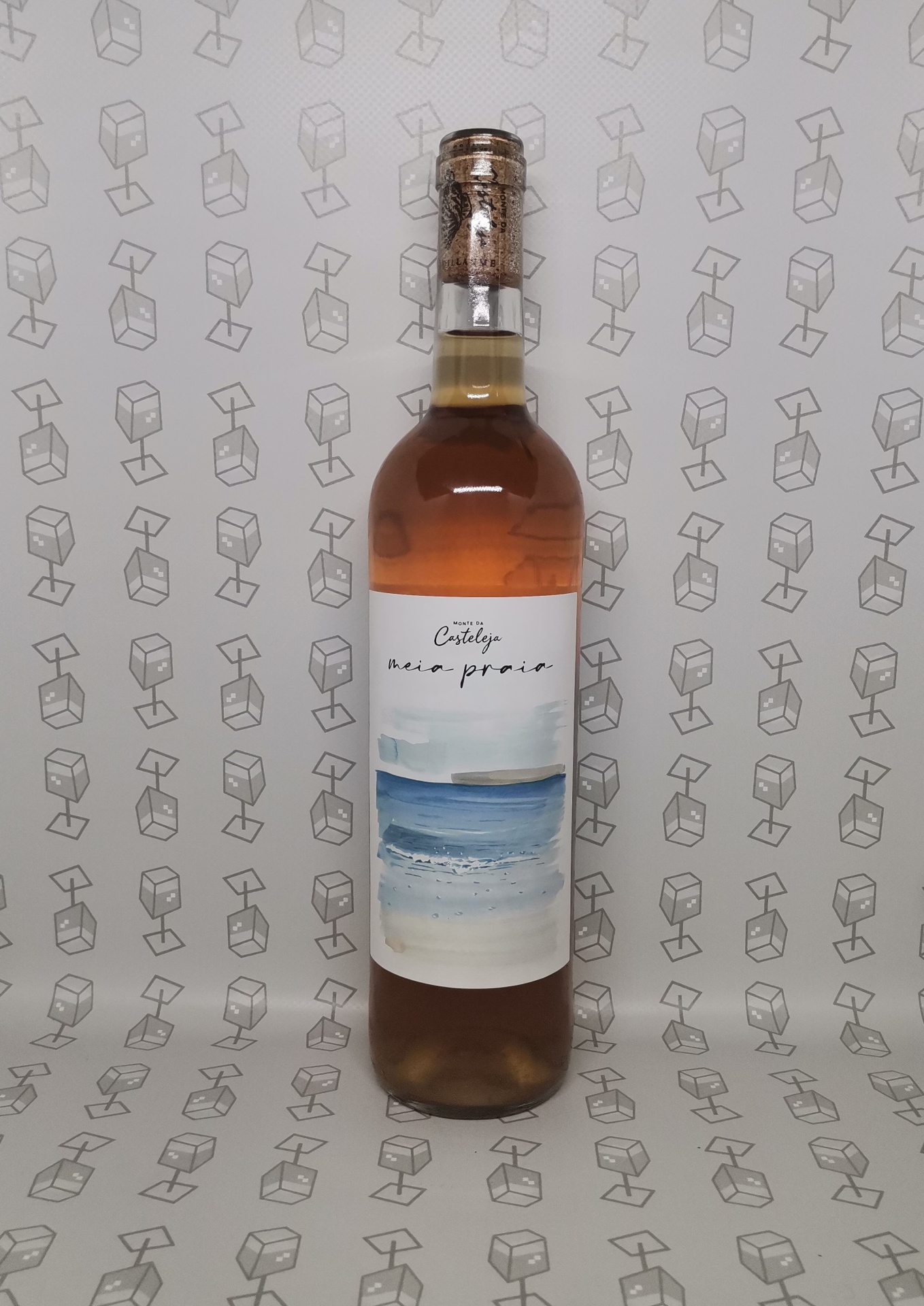 Garrafa de líquido âmbar com rótulo azul e branco e tampa de cortiça em fundo com padrão de caixas