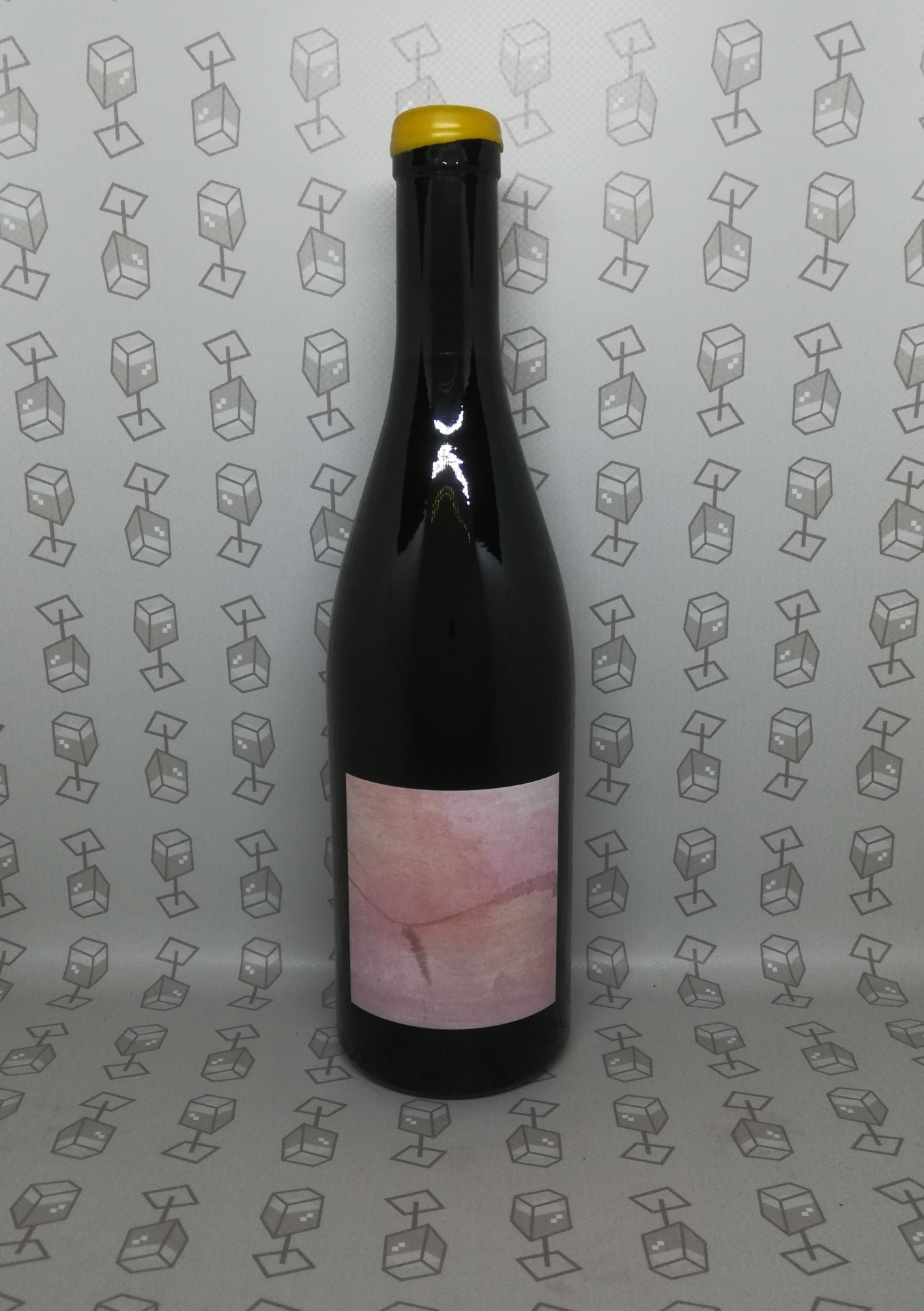Garrafa de vidro escuro com rótulo rosa e tampa amarela