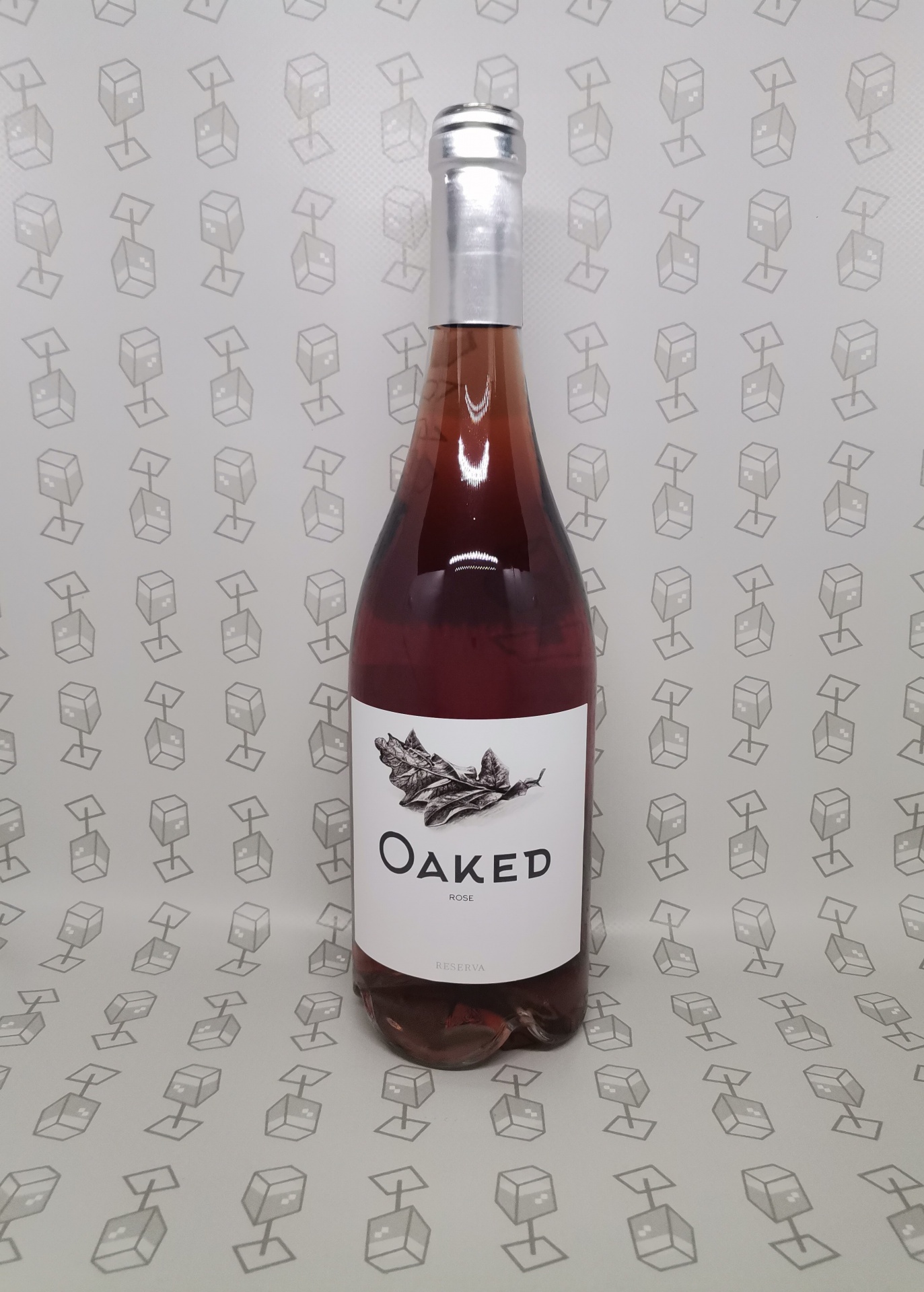 Garrafa de vinho rosé com rótulo branco e texto OAKED sobre fundo cinzento com padrão.