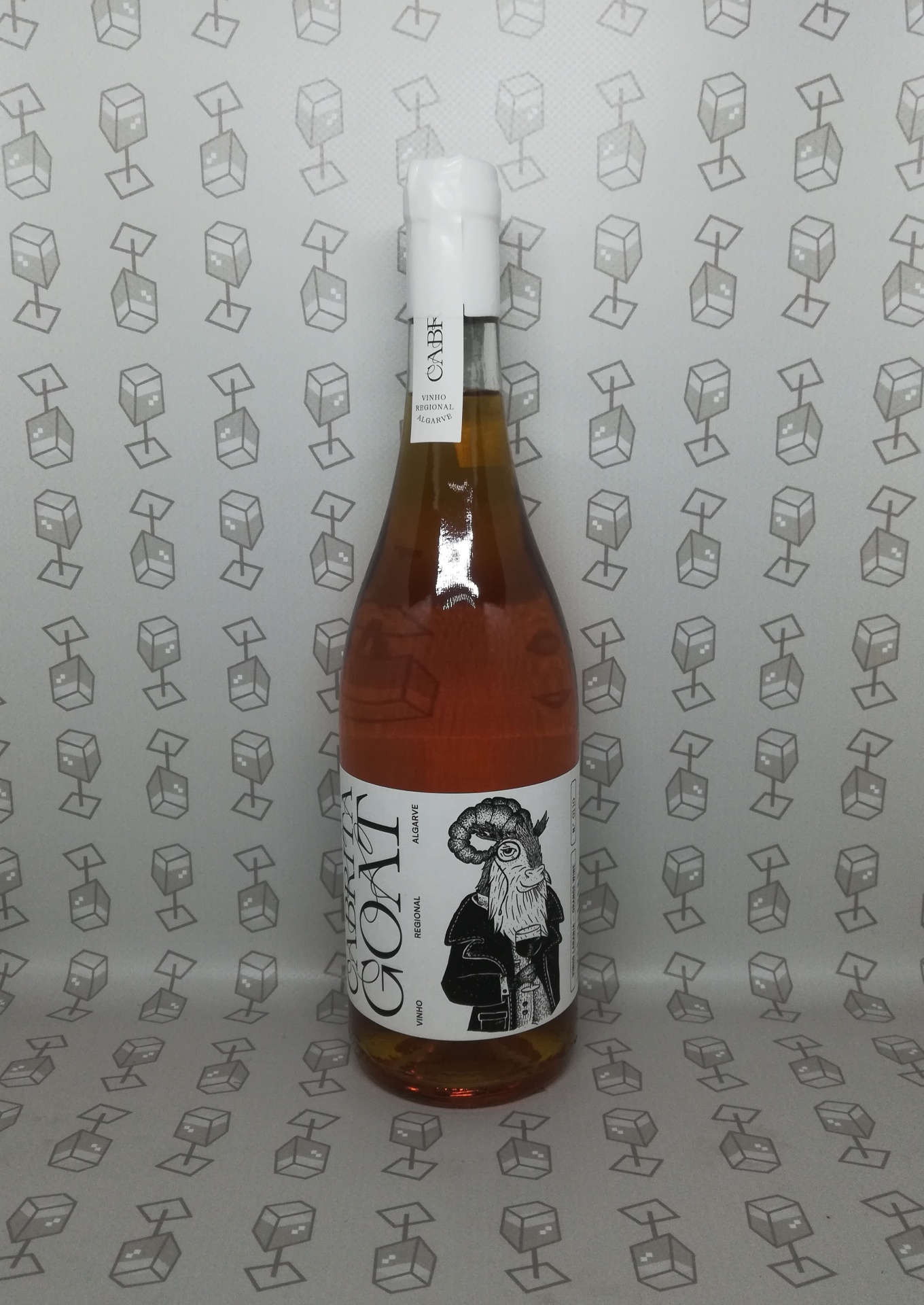 Garrafa de vinho rosé com rótulo ilustrado de bode e fundo com padrão de caixas desenhadas
