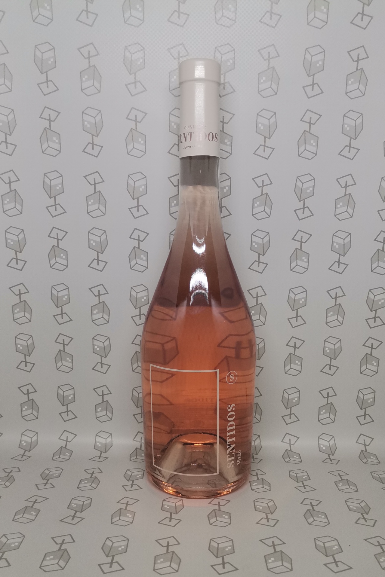Garrafas de vinho rosé transparentes com rótulos cinzentos e texto SOMATIVOS, sobre fundo cinzento com padrão de caixas.