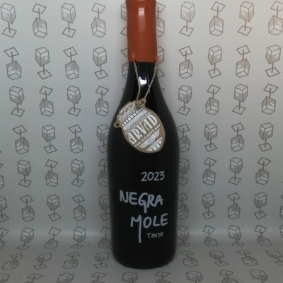Garrafa de vinho tinto Negra Mole 2023 com selo pendurado e fundo padrão caixas de vinho