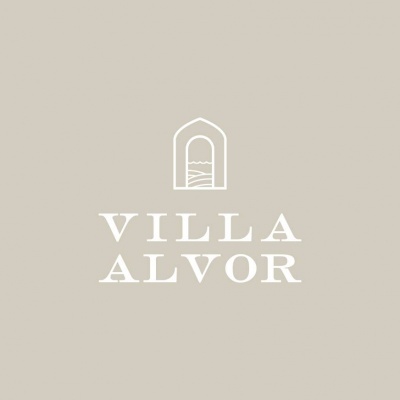 Logótipo VILLA ALVOR em branco sobre fundo bege claro com símbolo de janela/arco