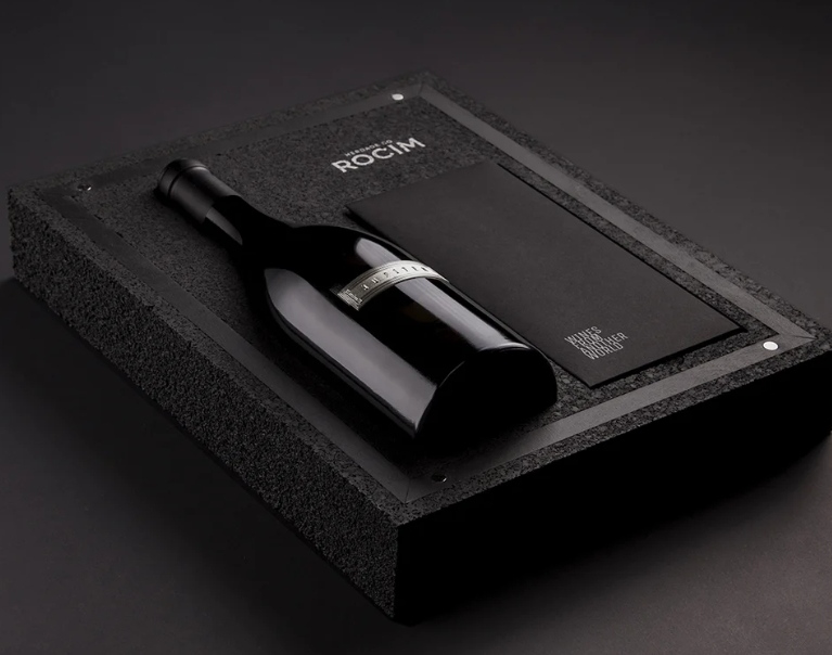 Garrafa de vinho tinto em caixa preta com envelope