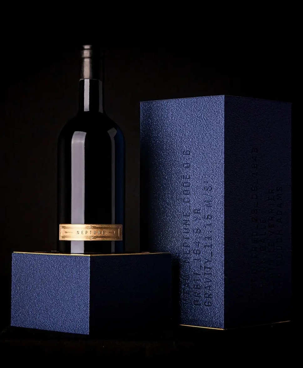Garrafa de vinho escura com rótulo dourado e caixa azul texturada