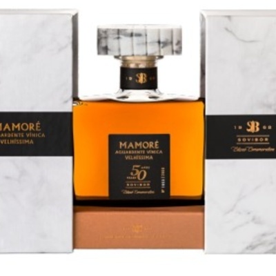 Frasco de aguardente Mamoré entre caixas brancas com padrão de mármore
