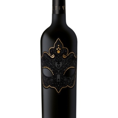 Garrafa de vinho preta com rótulo decorado com máscara veneziana dourada e preta.