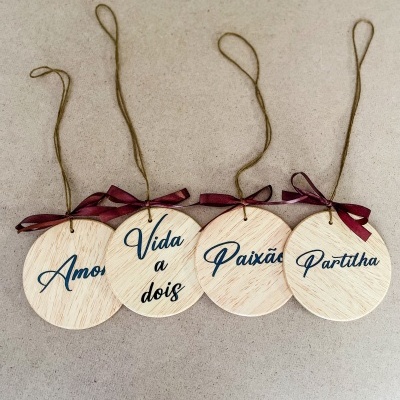 Ornamentos de madeira com palavras em português e laços vermelhos para pendurar