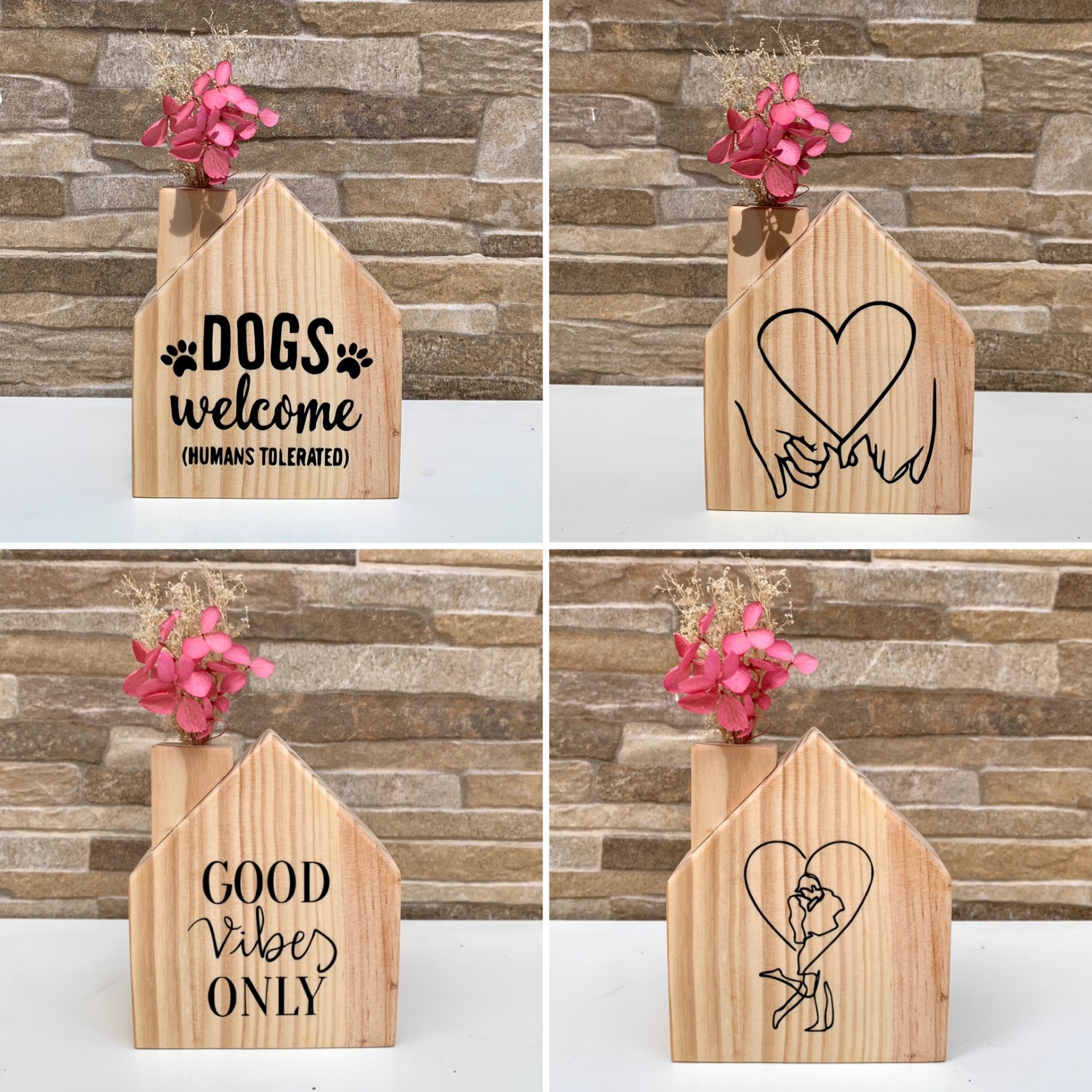 Objetos decorativos de madeira em forma de casa com textos e desenhos, contendo flores secas cor de rosa.