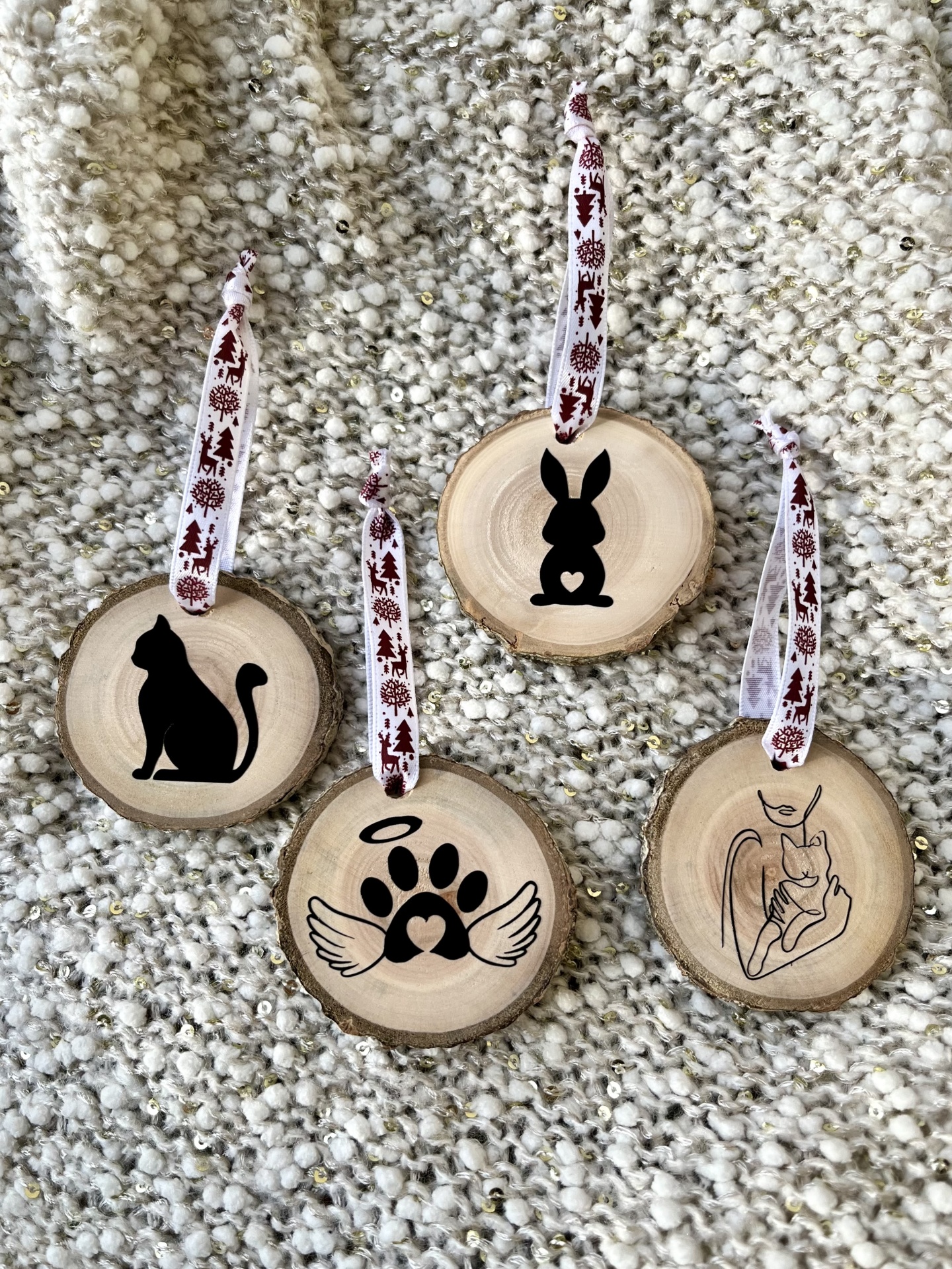 Decorações redondas em madeira com desenhos de animais e símbolos em preto e fitas brancas e vermelhas.