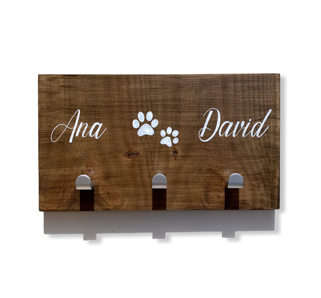 Quadro de madeira com três ganchos e nomes Ana e David com pegadas brancas
