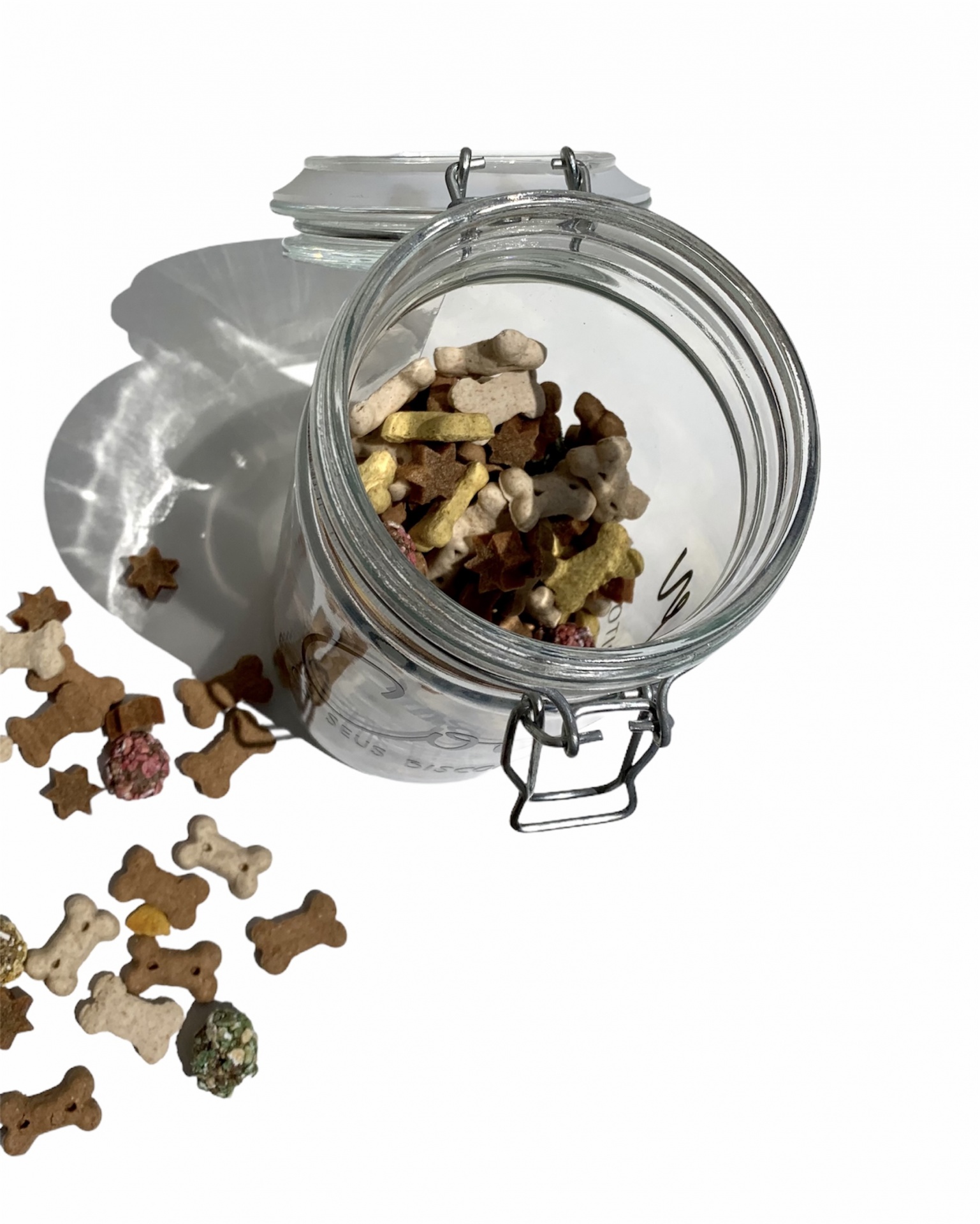 Frasco de vidro com biscoitos para cães coloridos em forma de ossos e estrelas