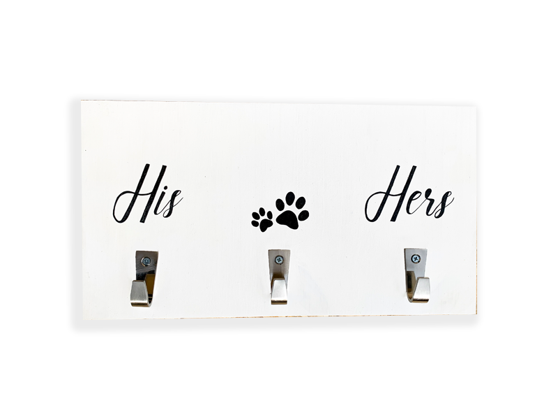 Placa branca com três ganchos metálicos rotulados com 'His', 'Hers' e uma pata de animal