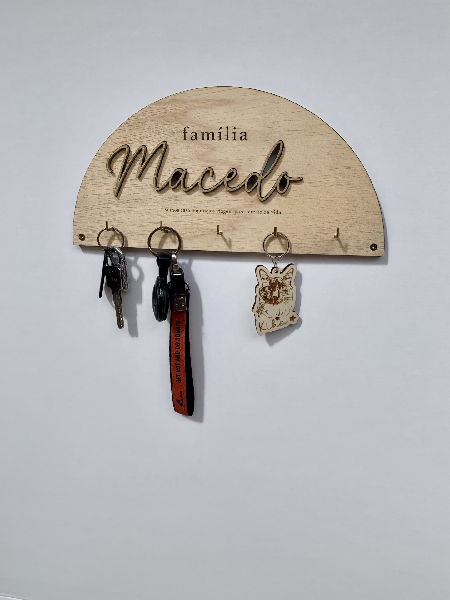Móvel de parede semicircular em madeira clara com ganchos e porta-chaves pendurados