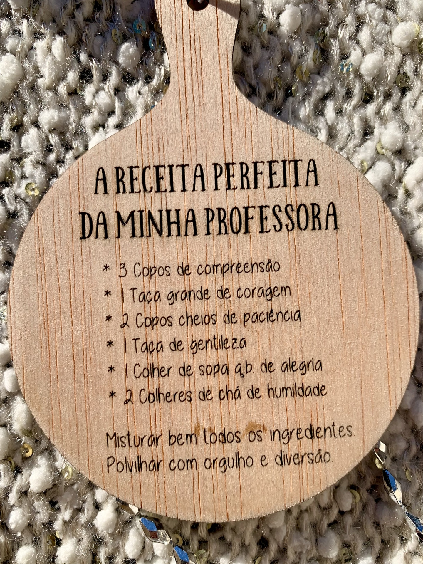 Tábuas de madeira com texto gravado 'A RECEITA PERFEITA DA MINHA PROFESSORA' sobre tecido felpudo