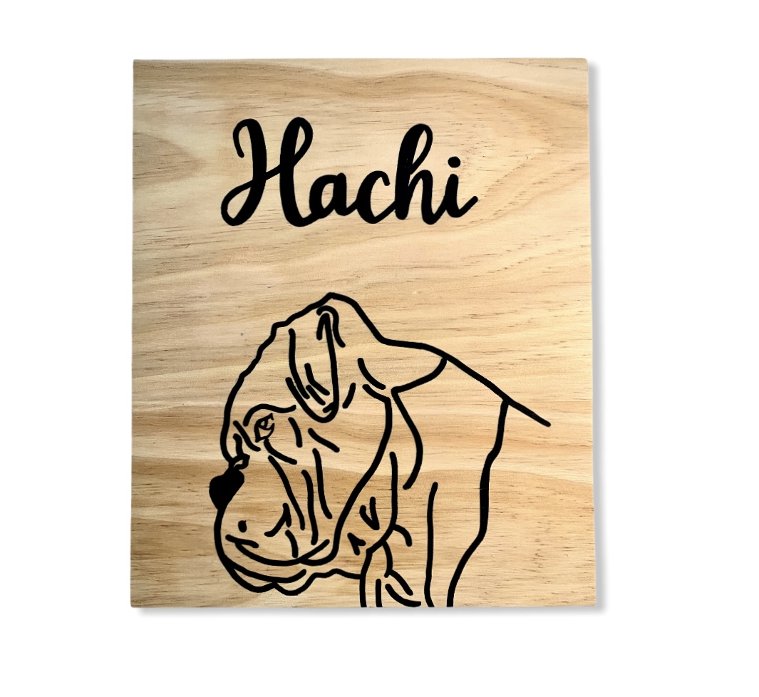 Placa de madeira com nome 'Hachi' e desenho de cão em preto