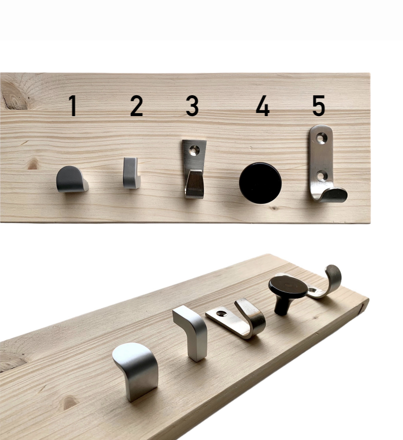 Cinco ganchos metálicos diferentes fixados numa placa de madeira clara