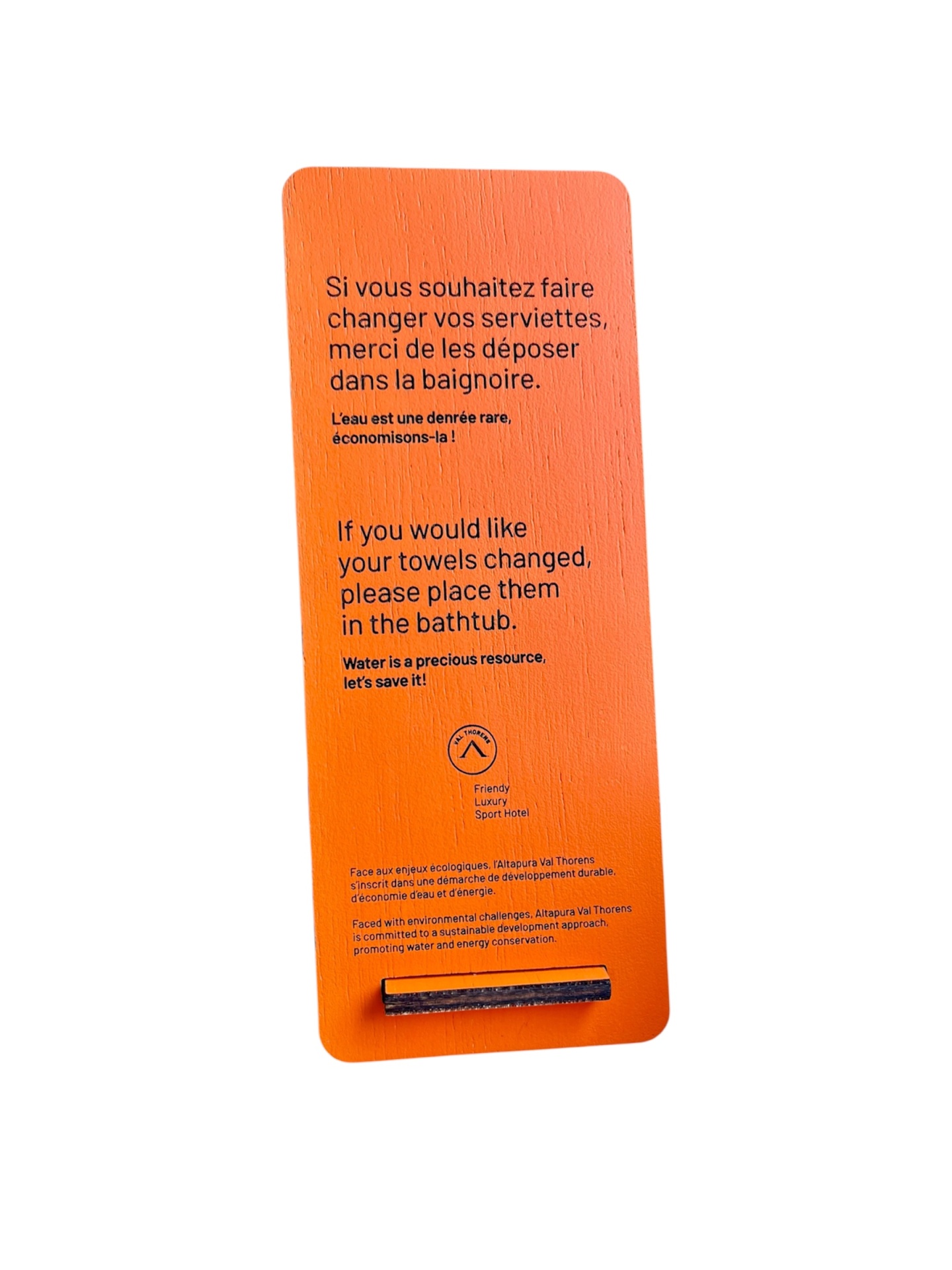 Prancha de madeira laranja com texto em francês e inglês sobre troca de toalhas