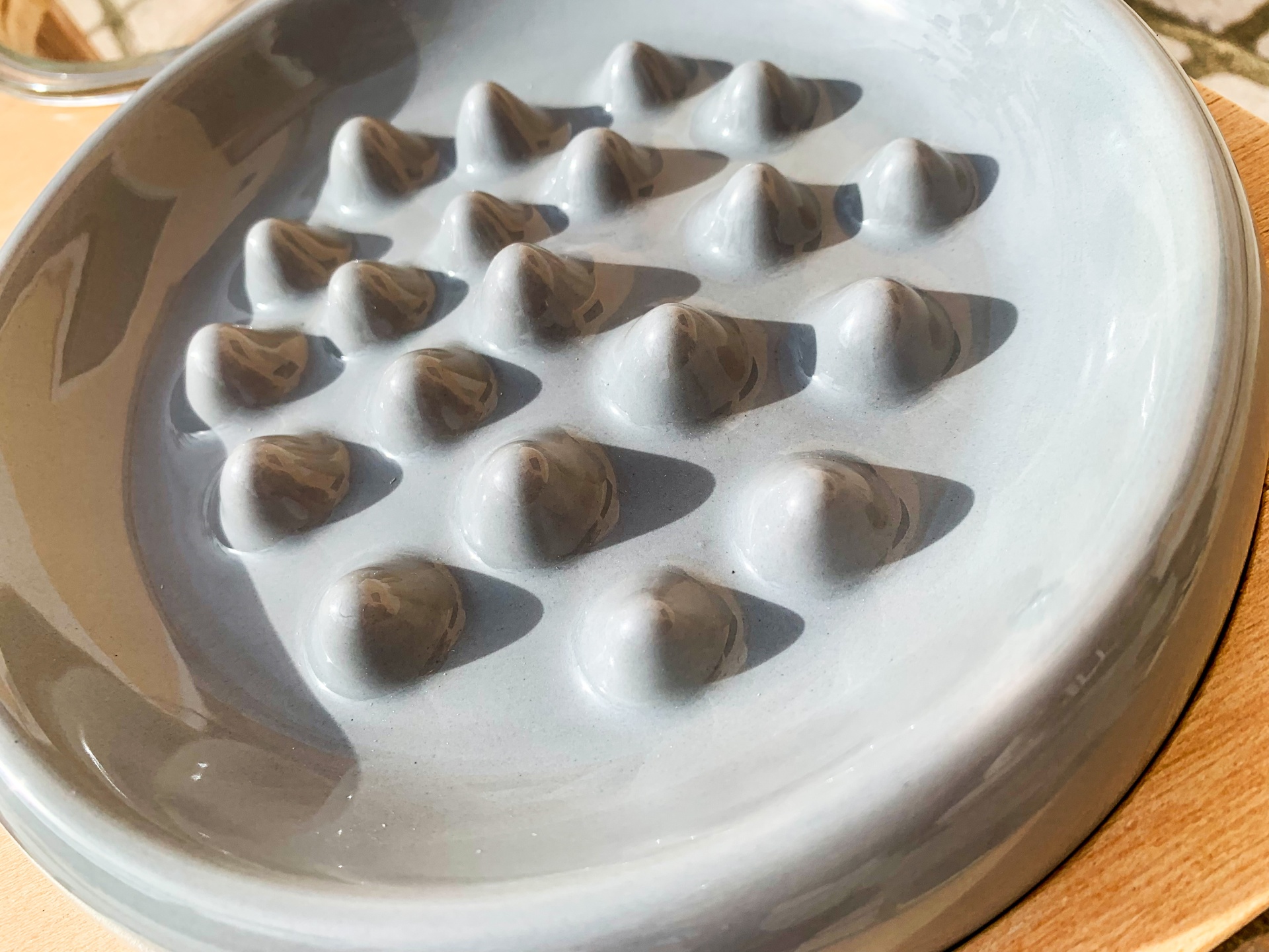 prato redondo de cerâmica branca com relevo e base de madeira clara