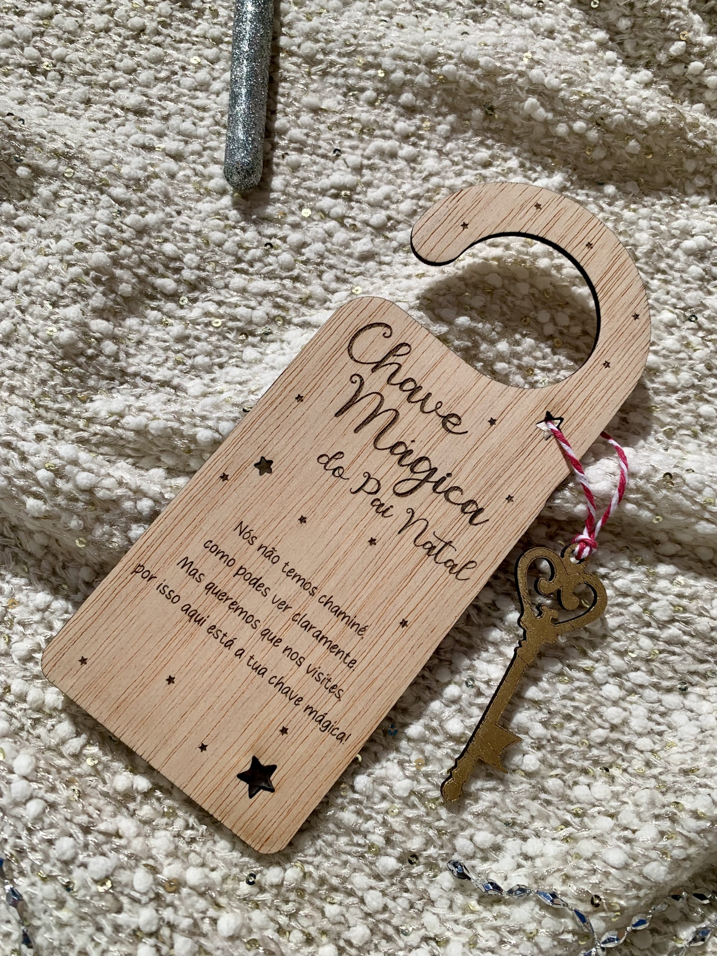 Pendurador de madeira com chave metálica sobre tecido bege.