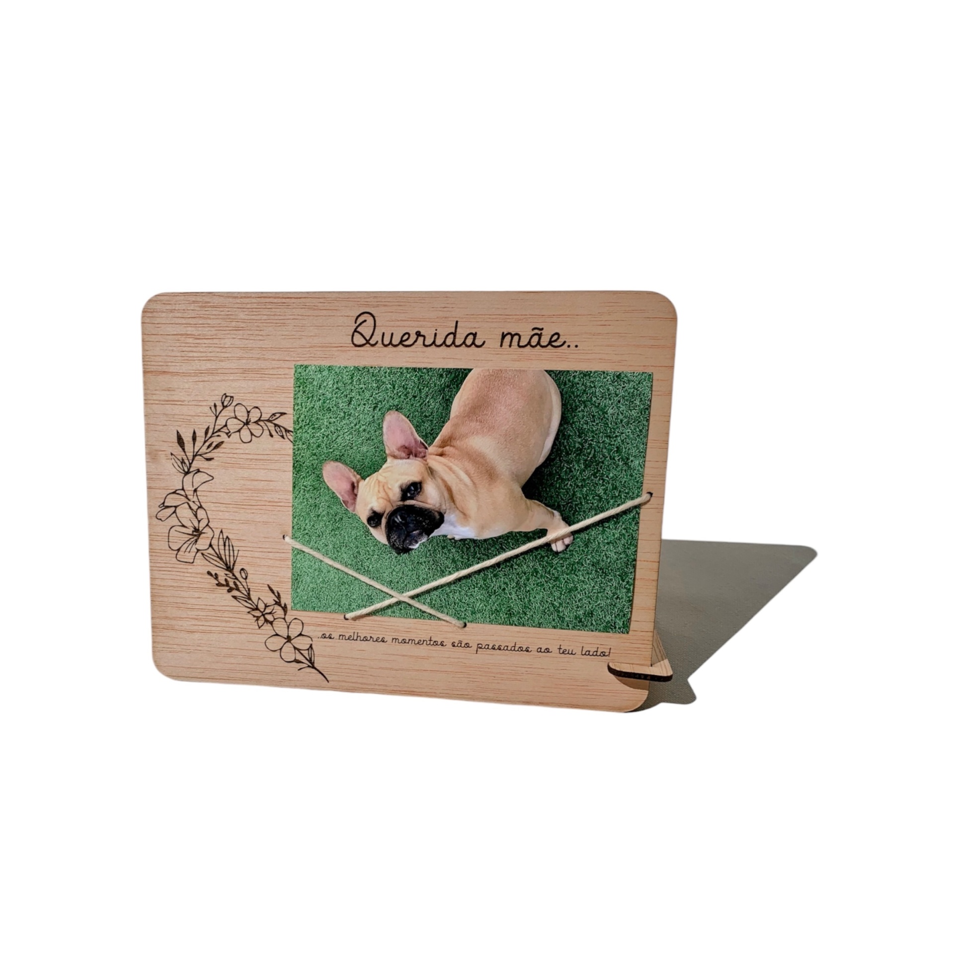 Moldura de madeira clara com um cão pequeno rodeada por decoração floral e texto Querida mãe..