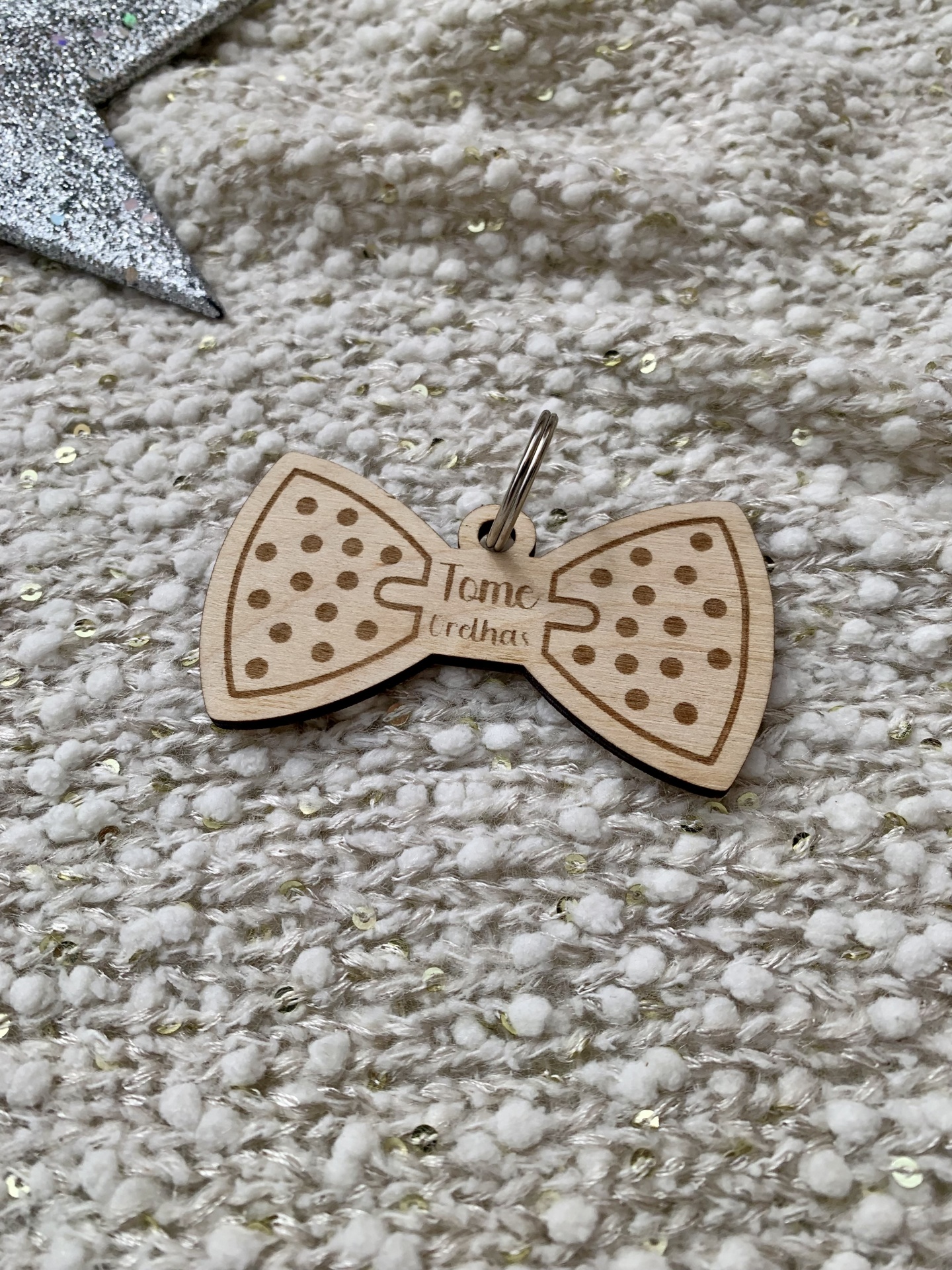 Pendente de madeira em forma de laço com padrão de pontos e texto gravado