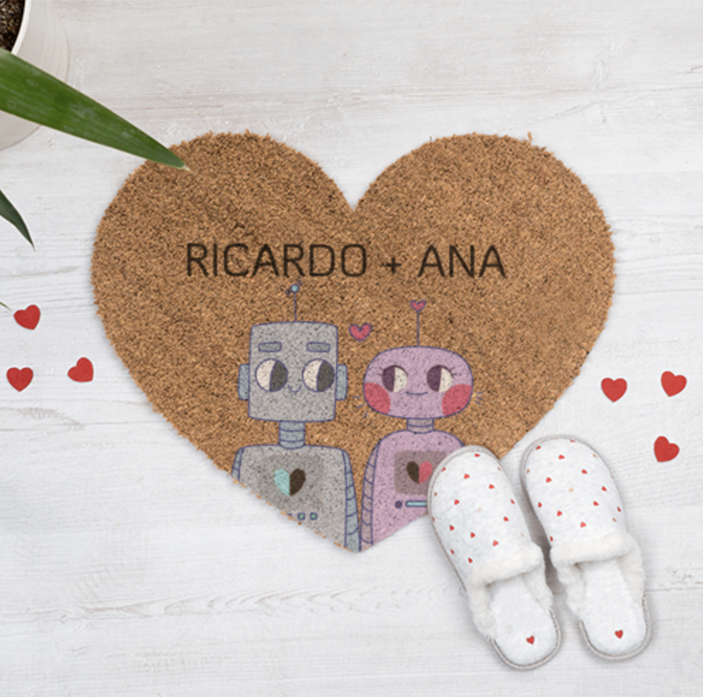 Tapete coração com robôs e texto Ricardo + Ana próximo a chinelos brancos com corações vermelhos.