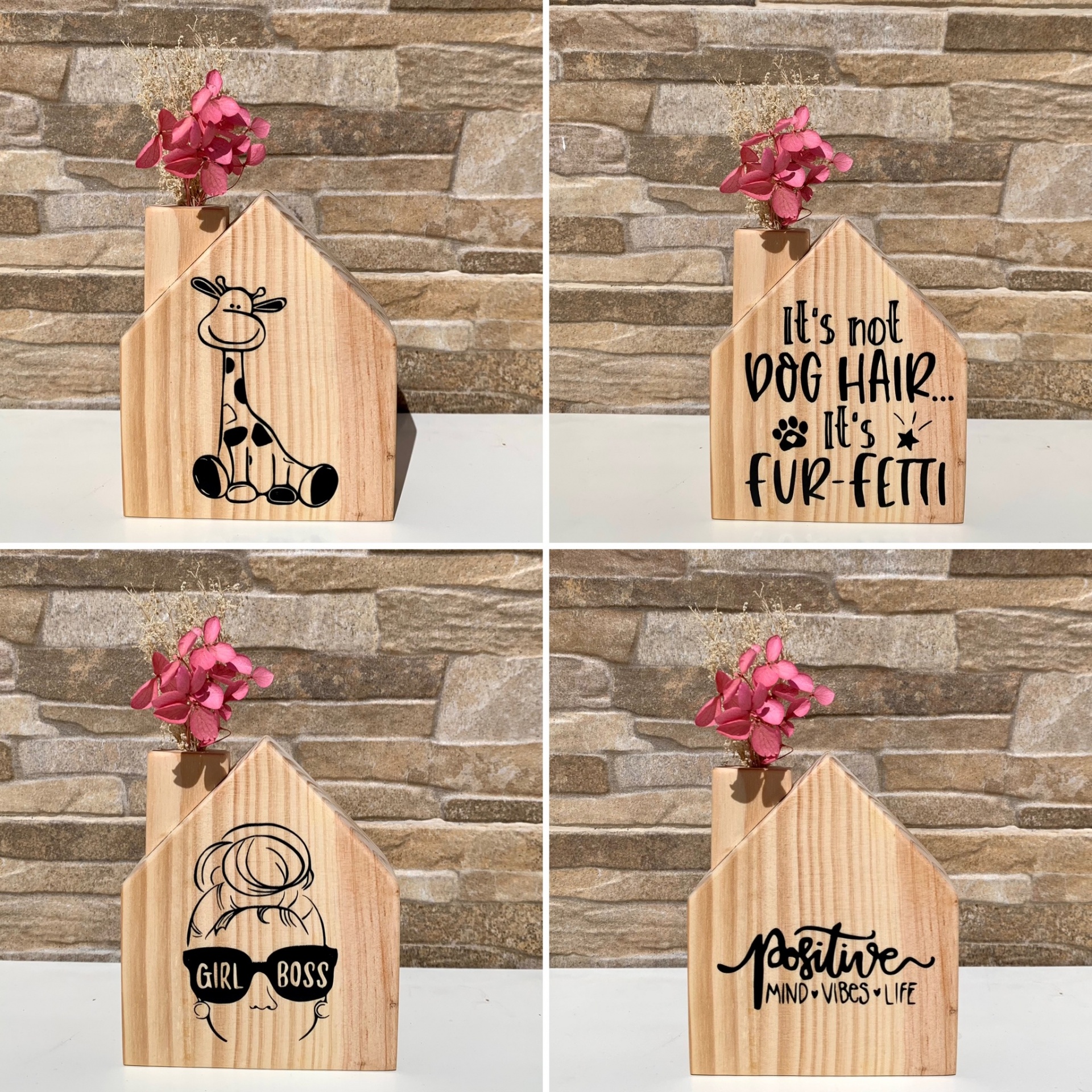 Quatro blocos decorativos de madeira em forma de casa com diferentes impressões e flores cor-de-rosa no topo