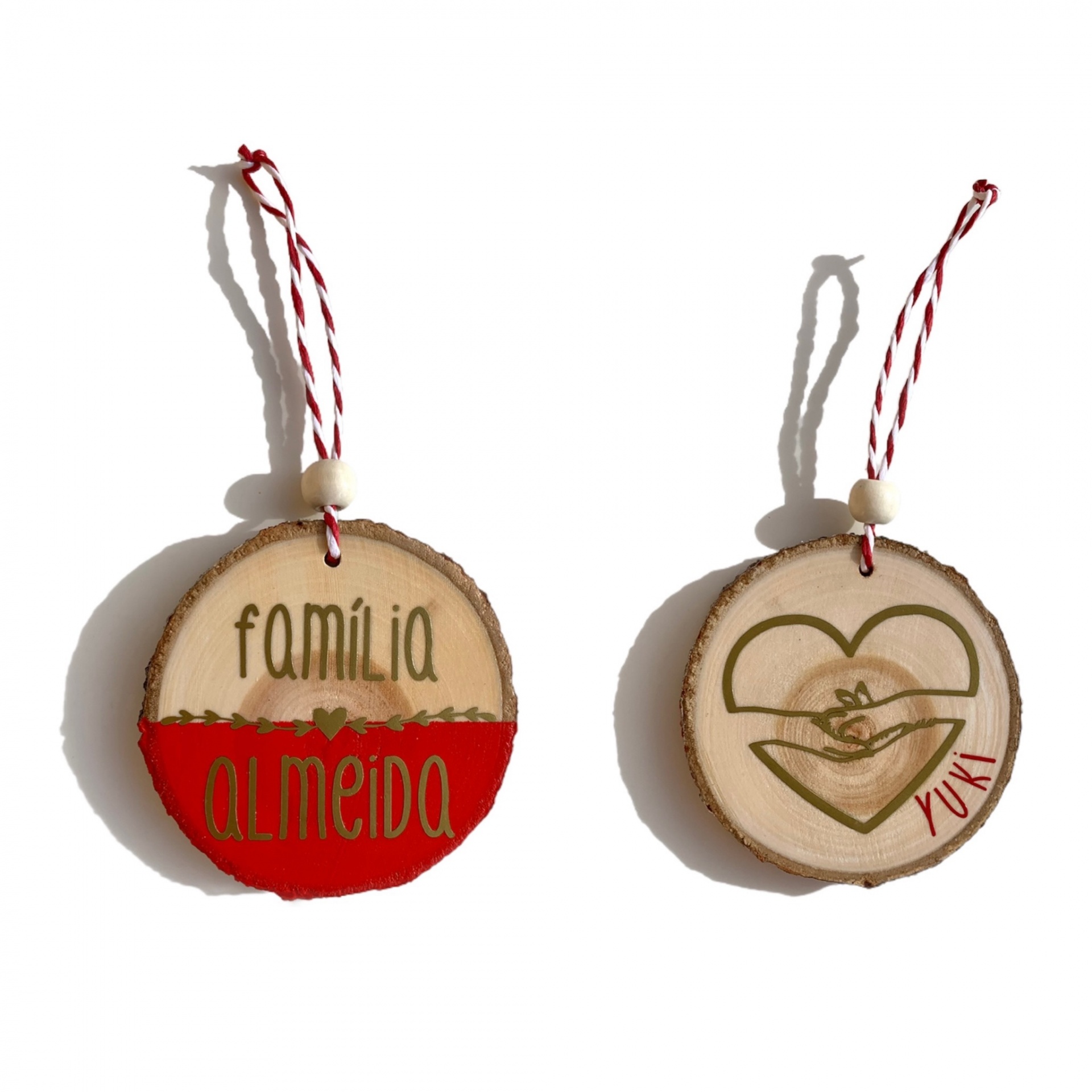 Dois ornamentos redondos de madeira com corda para pendurar, texto e desenho decorativos.