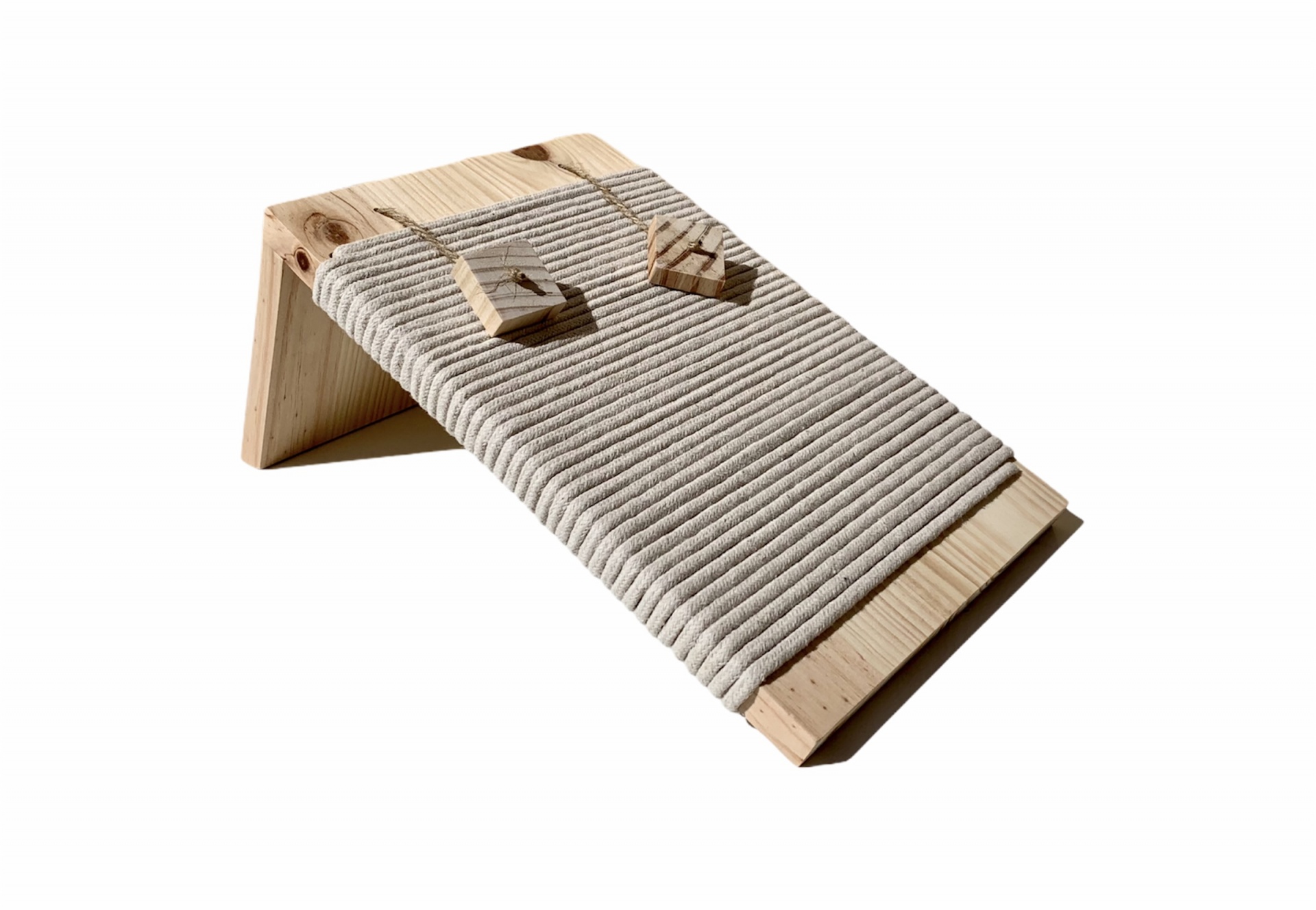 Banco inclinado em madeira clara com corda cinzenta enrolada e pequenos objetos triangulares de madeira