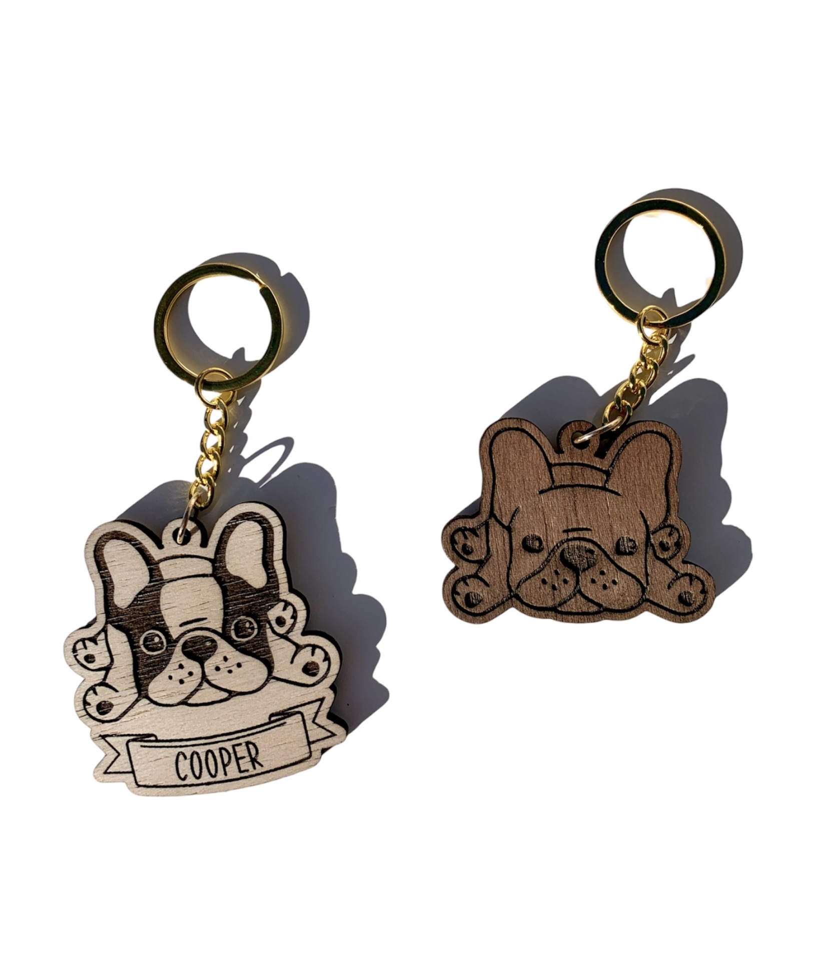 Dois porta-chaves de cabeça de bulldog francês, um beige com o nome COOPER e outro castanho