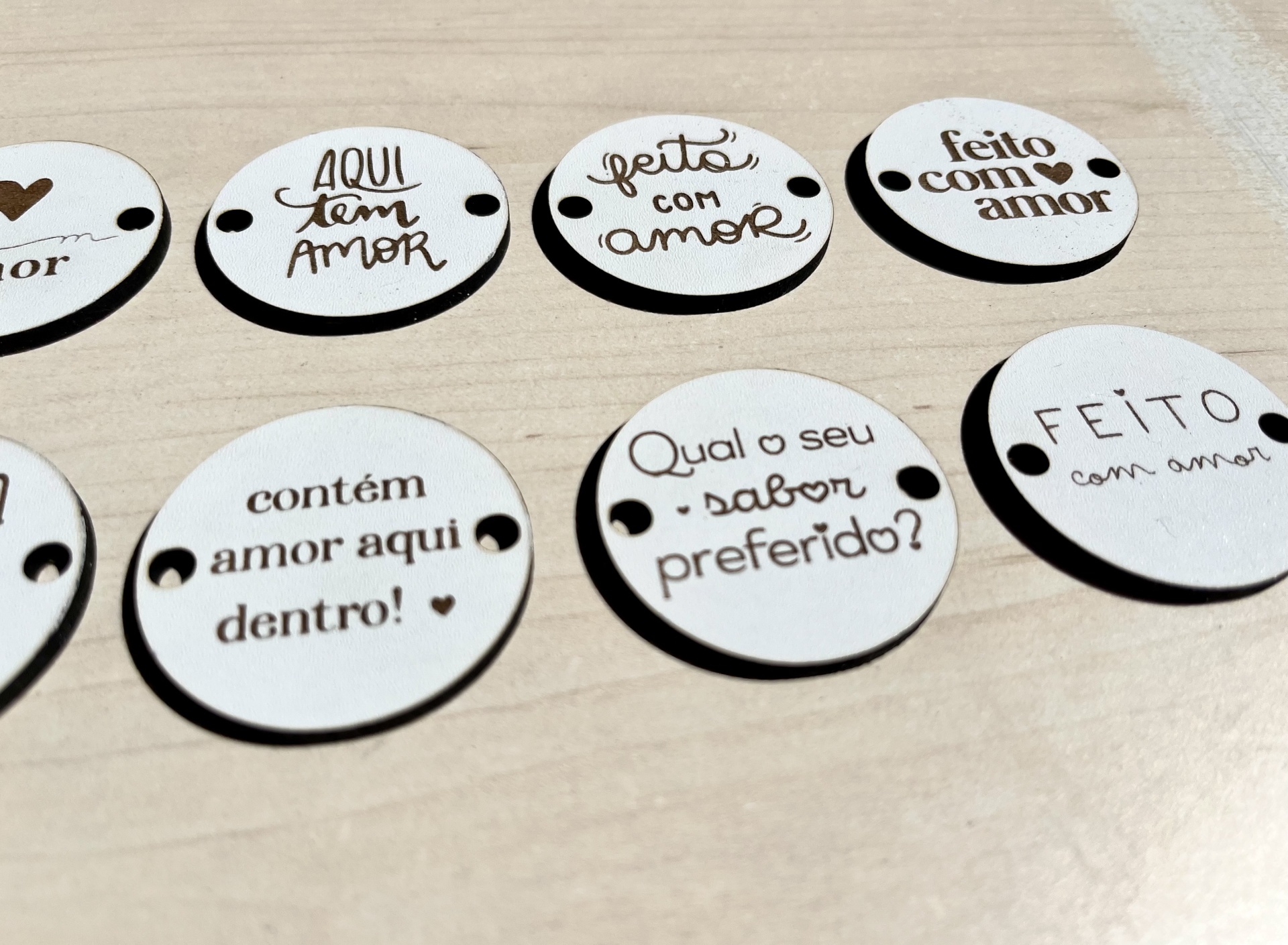 Placas redondas em madeira branca com texto gravado relacionado ao tema amor.